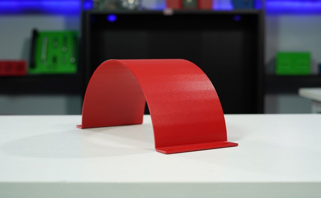 Red bent sheet metal part demonstrating precision bending techniques